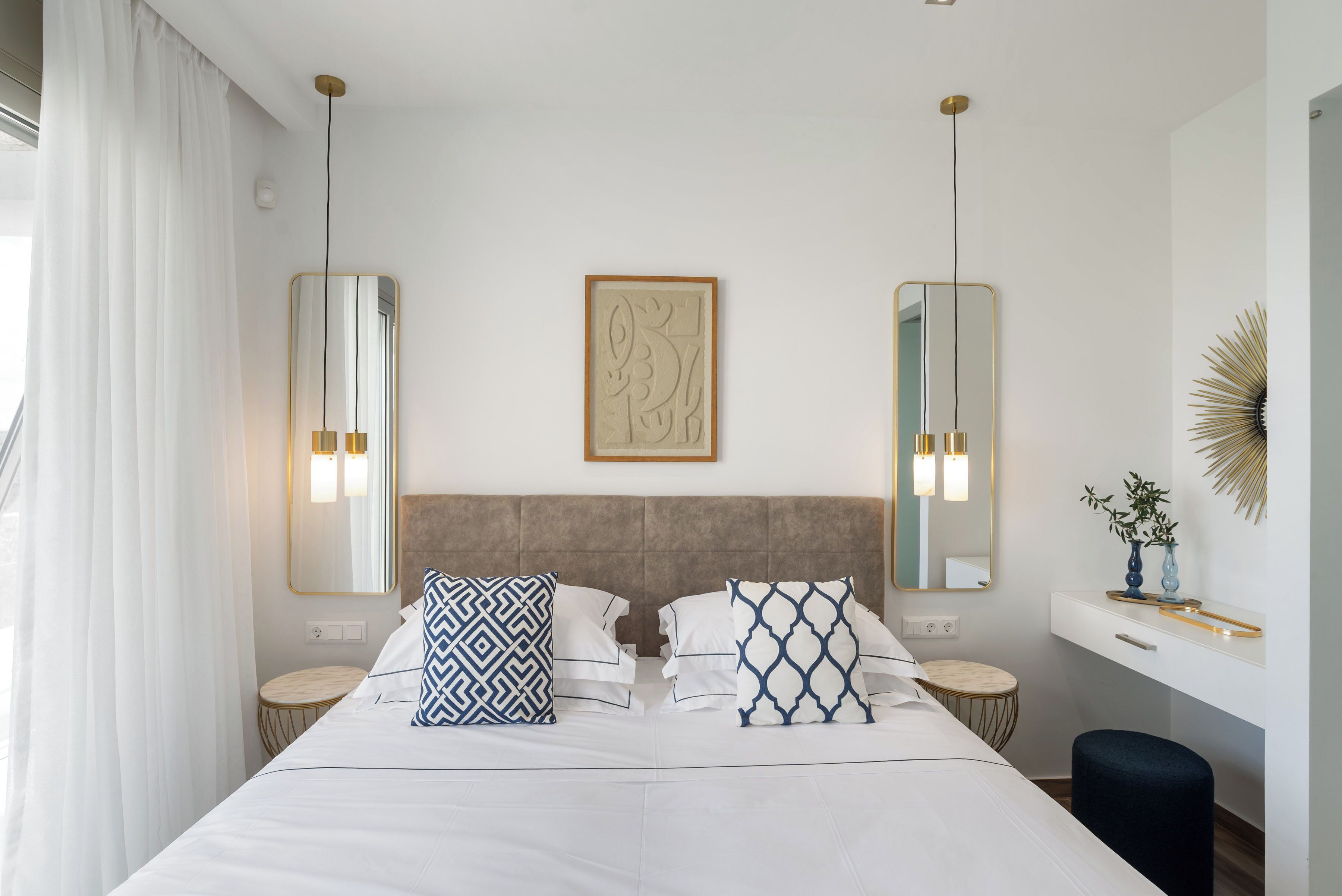 A hotel room with a large bed, two bedside tables, a nightstand, a dresser, and a mirror.