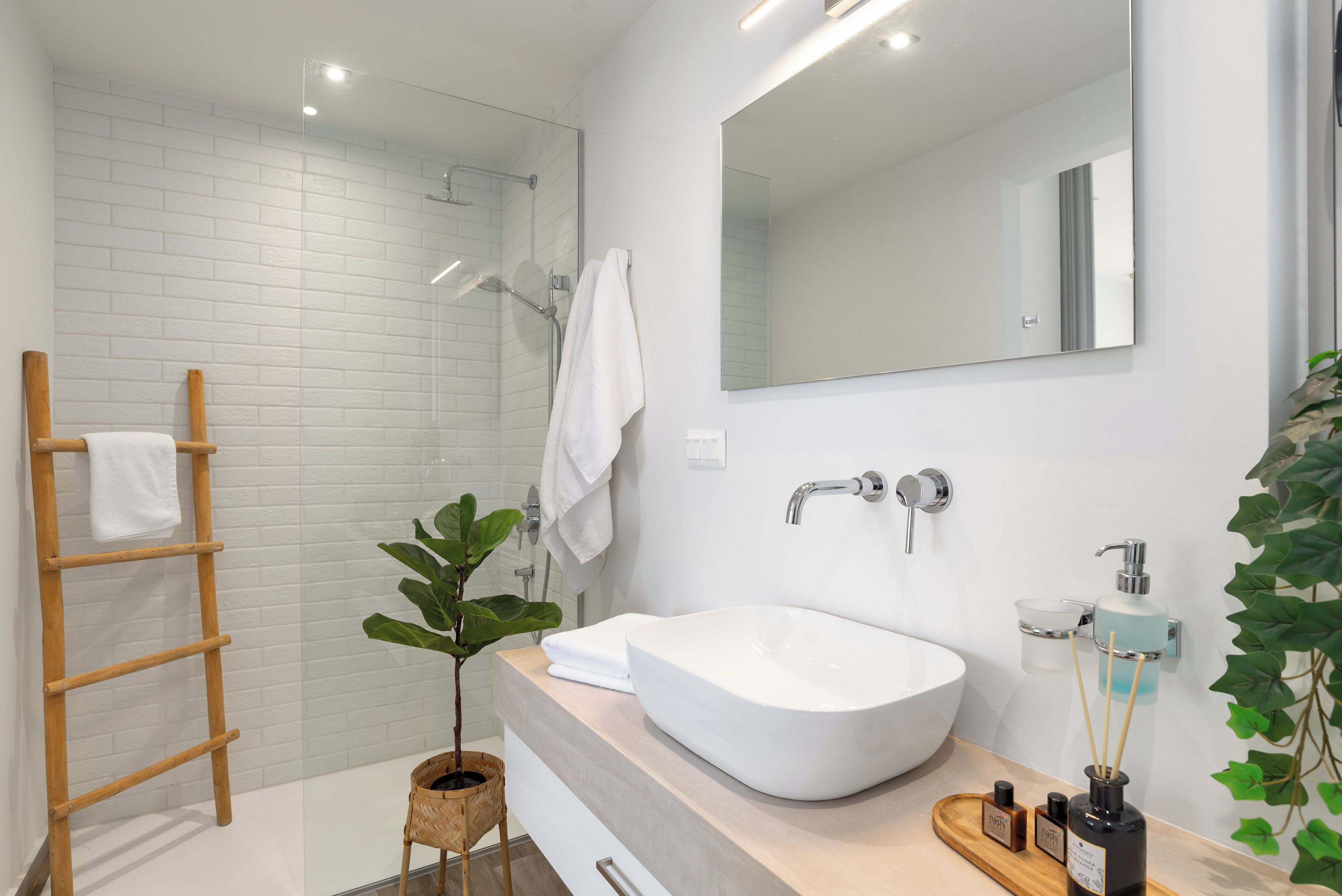 A modern bathroom with a white sink, a large mirror, and a glass-enclosed shower.