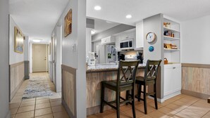 Una cucina moderna con mobili bianchi, un'isola in legno e sgabelli da bar.