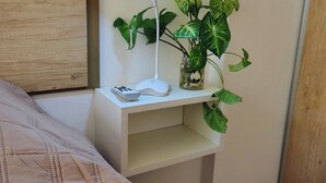 Et pænt indrettet soveværelse med seng, et sengebord med lampe, en lille plante og en træsenggavl.