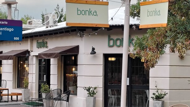 En bygning hvor der står 'bonka' på skiltet over indgangen. Der er udendørs siddeområder med borde og stole.