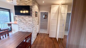 A modern kitchen with a stone wall, wooden dining table, and chairs. - Fully furnished flat in a lovely villa (Bergisch Gladbach)