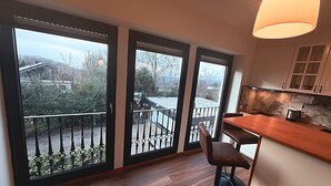 A modern kitchen with a wooden countertop, a bar stool, and a view of a balcony with a railing. - Fully furnished flat in a lovely villa (Bergisch Gladbach)