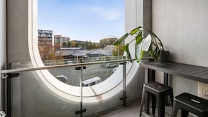 Parveke, jolta avautuu näkymä kaupungin ylle, ruukussa oleva kasvi ja pieni pöytä, jonka ympärillä on kaksi jakkaraa.