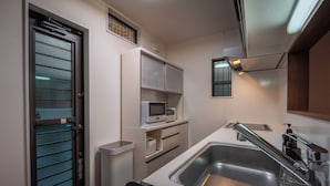 A compact kitchen with a stainless steel sink, a microwave, and a built-in oven. - Private Residence Kyoto Station North (Kyoto)