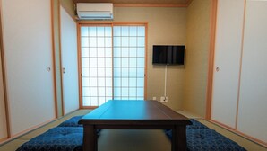 A traditional Japanese room with tatami flooring, a low table, and sliding doors. - Private Residence Kyoto Station North (Kyoto)