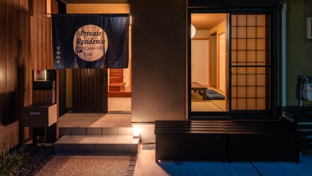 A private residence entrance with a sliding door, a small outdoor seating area, and a banner indicating the location in Kyoto, Japan. - Private Residence Kyoto Station North (Kyoto)