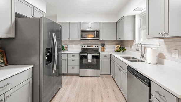 A modern kitchen with stainless steel appliances, light grey cabinetry, and a white countertop. - 5RM2BA,Game Rm,FirePit,Golf,BBall,Near Parris Island (Beaufort)