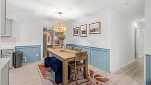 A dining area with a wooden table, chairs, a vase with flowers, and framed pictures on the wall. - 5RM2BA,Game Rm,FirePit,Golf,BBall,Near Parris Island (Beaufort)