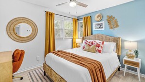A bedroom with a bed, a chair, a bedside table with a lamp, a ceiling fan, and a window with curtains. - 5RM2BA,Game Rm,FirePit,Golf,BBall,Near Parris Island (Beaufort)
