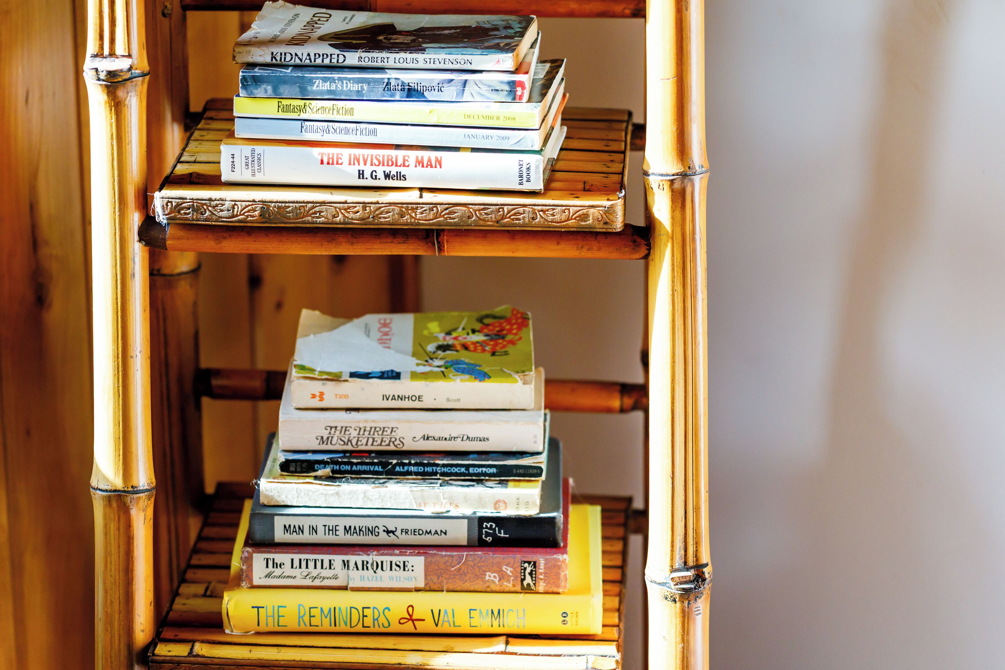 Une bibliothèque en bambou à plusieurs étagères, où sont rangés différents livres.