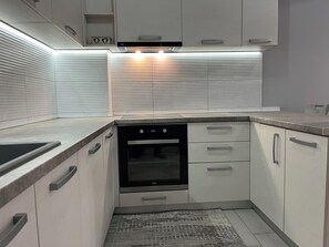 Moderni keittiö, jossa on integroidut kodinkoneet, ruostumattomasta teräksestä valmistettu uuni ja mikroaaltouuni.