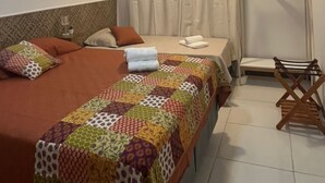 A hotel room with a bed, a ceiling fan, an air conditioning unit, a shower area, and a wooden chair. - Vacation Rental for Carnival - Furnished Apartment" "Carnival 2026 (salvador)