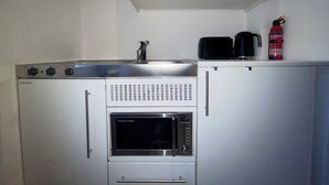 Uma cozinha compacta equipada com micro-ondas, forno e pia.