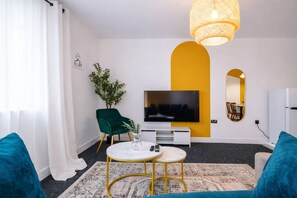 Ein modernes Wohnzimmer mit Fernseher, Essbereich und Spiegel.