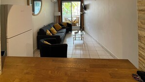 A compact living space with a kitchen area, a dining table, and a sofa with yellow cushions. - Quiet, functional apartment - ideal for couples/families (Saint-Paul)