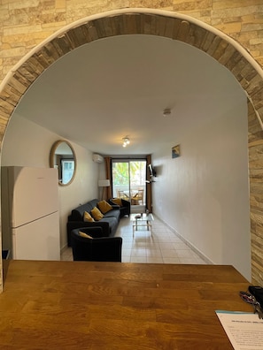 A compact living space with a kitchen area, a dining table, and a sofa with yellow cushions. - Quiet, functional apartment - ideal for couples/families (Saint-Paul)
