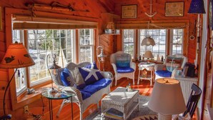 Un interior de cabaña acogedor con mobiliario de mimbre, ventanas amplias y decoración náutica.