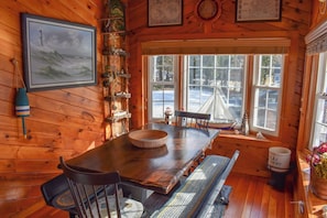 A wooden interior with a dining table, chairs, a bench, a window with a view of the outside, and nautical-themed decorations. - Charming 4 bedroom-Walk to Mayflower Beach (Dennis)