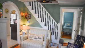 Una sala de estar acogedora con un sofá a rayas, una escalera y una cama en la habitación contigua.