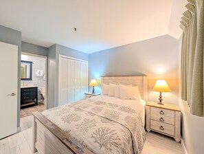 A bedroom with a bed, bedside tables, a wardrobe, and a bathroom visible in the background. - Myrtle Beach Resort B0338 (Myrtle Beach)