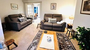 A living room with two dark sofas, a coffee table, and a rug. There is a door leading to another room and a plant in the corner. - Dogs Welcome Peaks Retreat · Views · 3BR · Sleep 5 (Matlock)