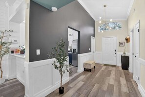 A spacious hallway with a dark wall, a white door, and a bench. - Lakefront Home w/ Private Pool & Scenic Views (Brandon)