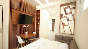Ein modernes Hotelzimmer mit einem Bett, einem Schreibtisch, einem Fernseher und einem Bücherregal.