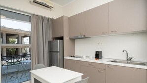 A modern kitchen with a white table and chairs, a stainless steel refrigerator, and a sink with a faucet. - Bed & Fligth (Markopoulo Mesogaias)