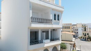 A two-story building with a balcony on the upper floor and a covered outdoor seating area on the ground floor. - Bed & Fligth (Markopoulo Mesogaias)