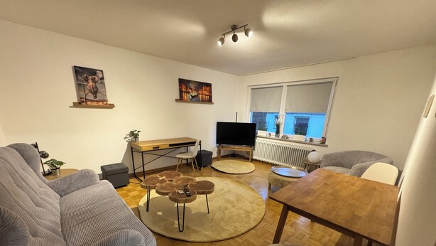Una sala de estar con sofá, mesa de centro, televisor y mesa de comedor.