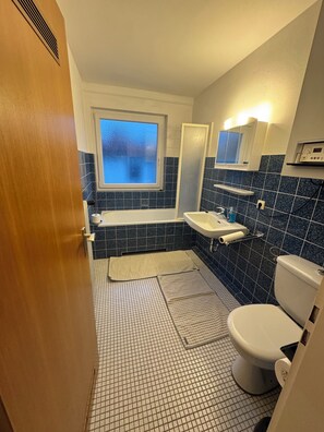 A bathroom with a bathtub, sink, and toilet. - 2-room apartment located in the Harz foreland, with living room & bedroom, kitchen + bathroom (Salzgitter)