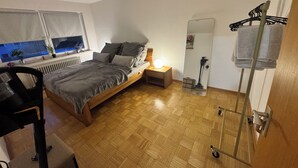 Un dormitorio con cama, mesita de noche, lámpara, radiador y espejo.