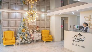 Un hall d'hotel amb una taquilla d'admissió, un arbre de Nadal i dues butaques grogues.