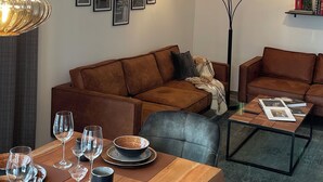 Een moderne woonkamer met een houten eettafel gedekt voor een maaltijd, twee banken en een salontafel.