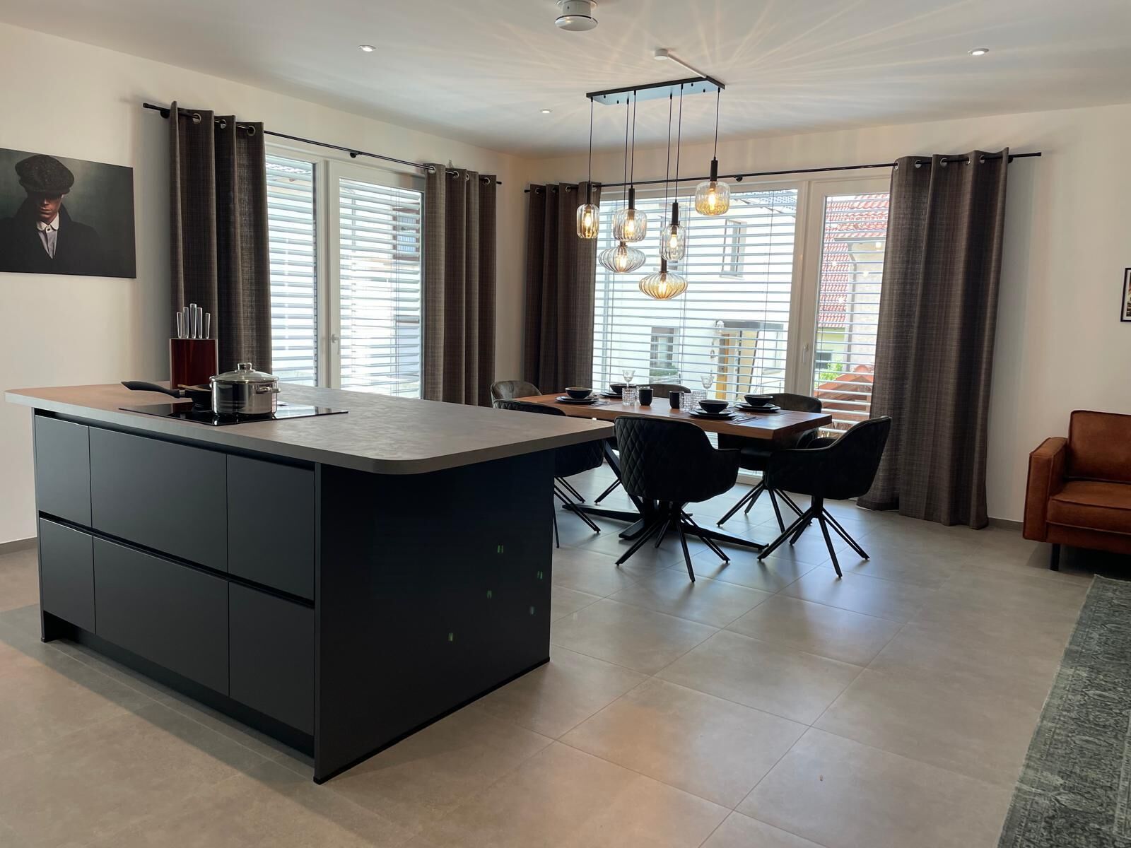 A modern kitchen with a central island, dining area with chairs, and a sofa.