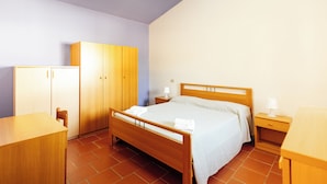 A hotel room with a wooden bed, a wooden wardrobe, a wooden desk, and a nightstand with a lamp. - Cottages surrounded by nature and relaxation in the Dauni Mountains (ROSETO VALFORTORE)