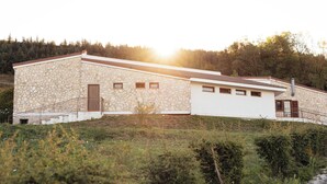 A stone building with a sloped roof, a staircase leading to the entrance, and a view of a forested hillside. - Cottages surrounded by nature and relaxation in the Dauni Mountains (ROSETO VALFORTORE)