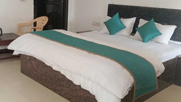 Un lit avec une couvre-lit blanche et turquoise, deux oreillers turquoise et une tête de lit en bois.