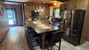 A modern kitchen with wooden cabinets, a large island with seating, and a built-in refrigerator. - Meadow Ridge Lodge 4 Season Getaway (Altmar)