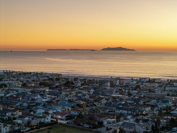 Une zone résidentielle côtière avec des maisons, une plage et une île visible au loin.