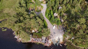 Vue aérienne d’un parc au bord d’un lac, avec une jetée en bois, un petit bâtiment et un chemin pavé.