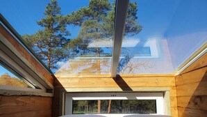 Une chambre avec une lucarne, des murs en bois et une vue sur les arbres.