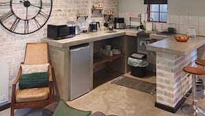 Een moderne keuken met een grote klok, inbouwapparatuur en een achterwand van natuursteen.