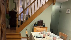 Een eethoek met een houten trap, een tafel gedekt voor vier personen en uitzicht op de woonkamer.