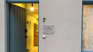 Een gevel met een deur, een nummerplaat en een lamp.