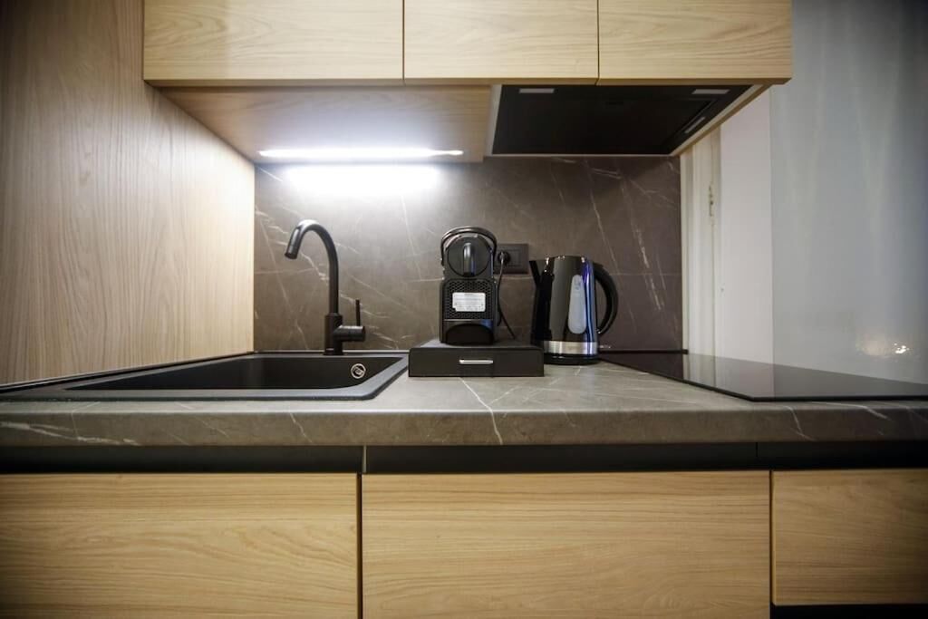 A modern kitchen with a built-in sink, a coffee maker, and a kettle.