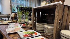 Une table à manger dressée avec des assiettes remplies de nourriture, des couverts et des assiettes empilées.