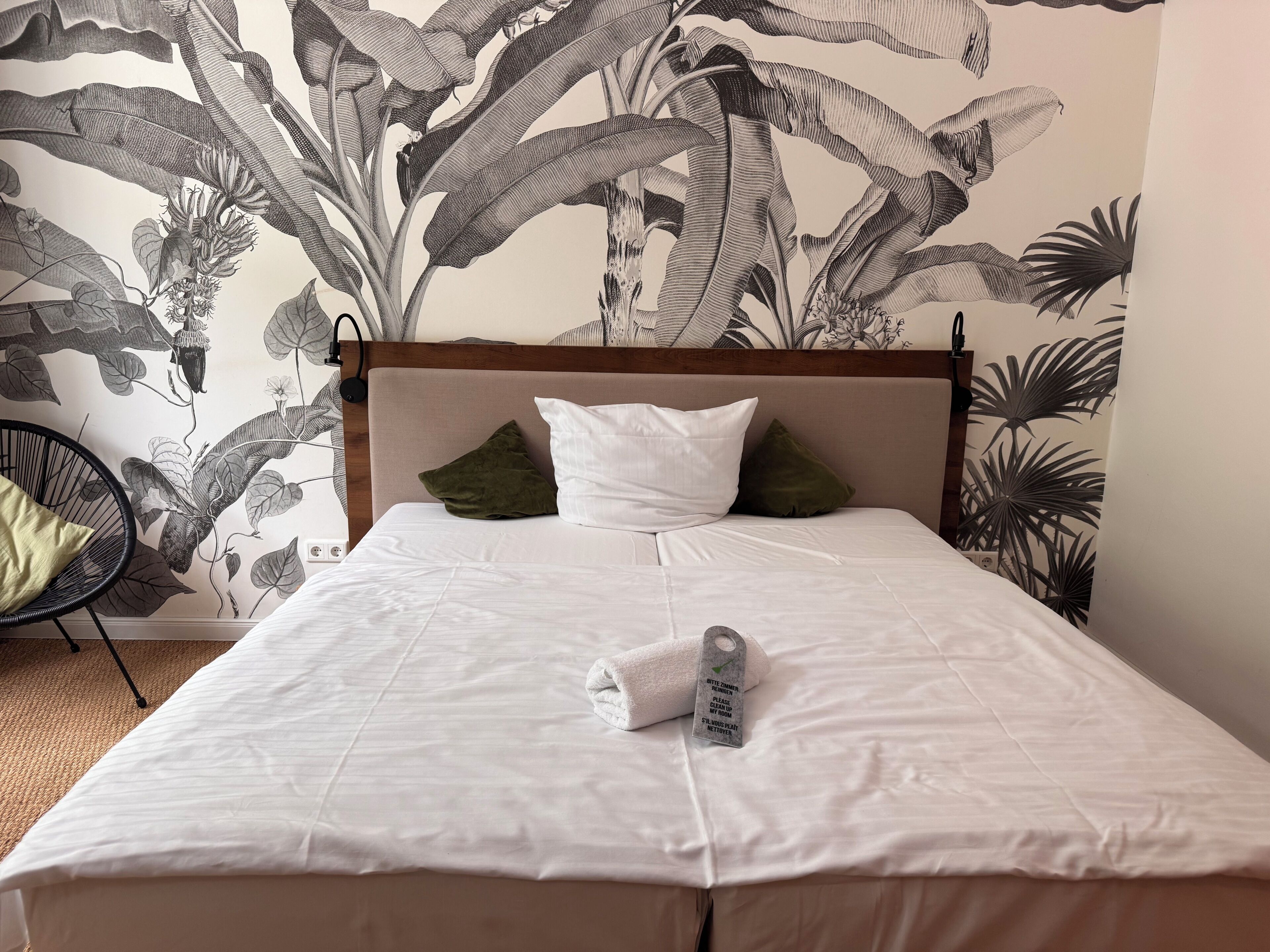 A neatly made bed with white bedding, a wooden headboard, and a tag indicating the bed size.