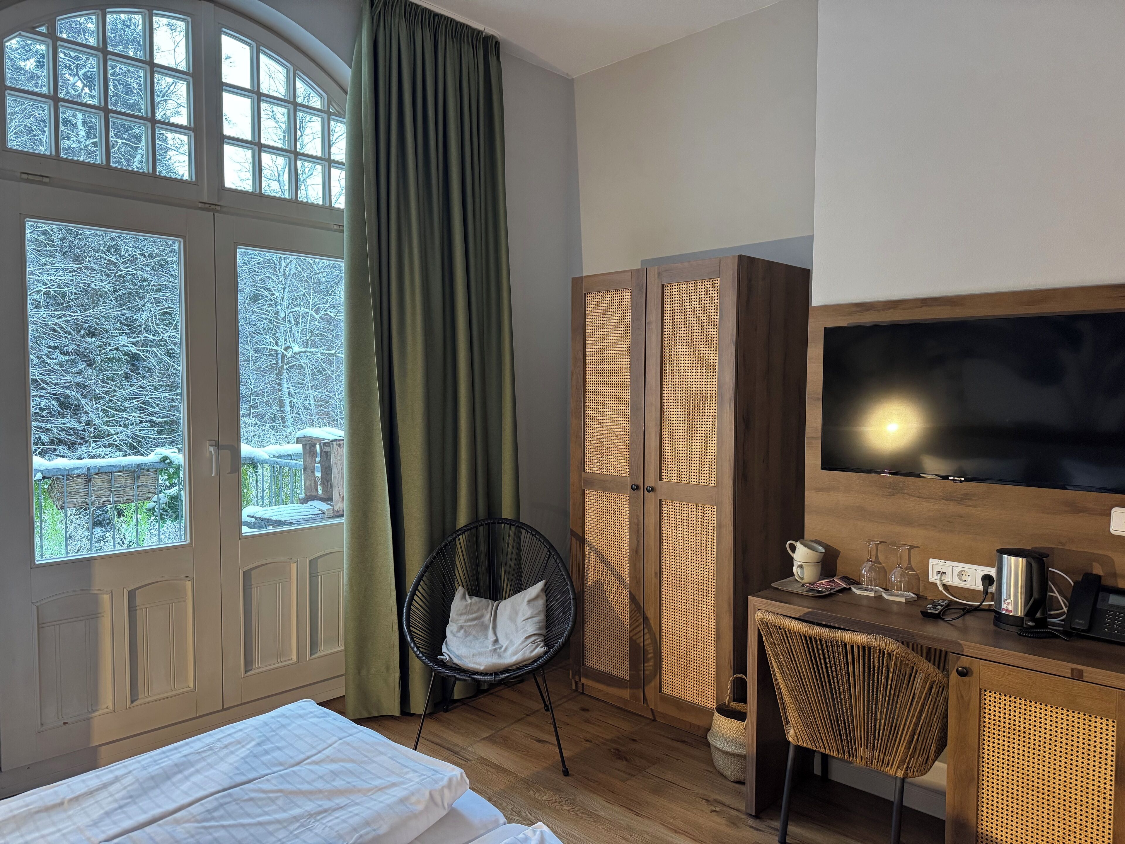 Una habitación de hotel con cama, escritorio con televisor, silla y armario.